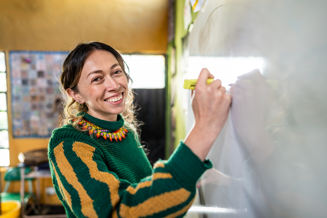 DS_VOCAB_iStock-2161654733 Educator smiles at whiteboard